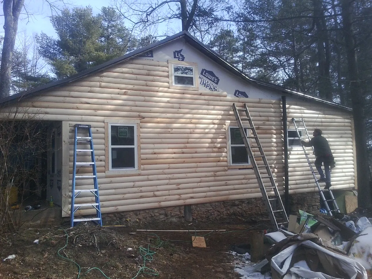 Ladders set against fresh log siding during an exterior remodel in Advance