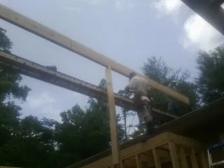 Carpenter setting a ridge beam over a new addition frame — Ice Dam Removal by Roofing Brothers in Advance