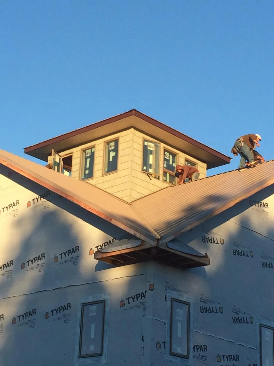 Roofers working around a rooftop cupola on a new metal roof at sunset — Roof Waterproofing in Advance by Roofing Brothers